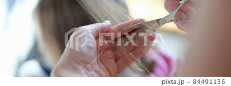 Master hairdresser cuts split ends of hair with scissors closeup 84491136