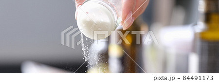 Woman hand pours fine salt into saucepan closeup Woman hand pours fine salt into saucepan closeup 84491173