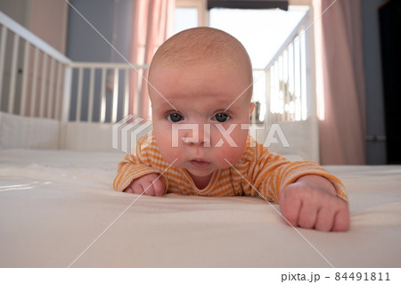 Funny caucasian baby lying on the bed. 84491811