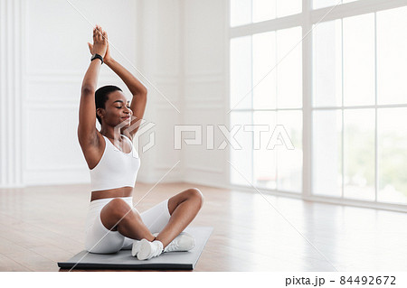 Young calm black woman sitting in lotus position on mat 84492672