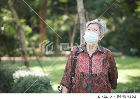 old elderly female elder woman wearing mask resting relaxing in garden. senior leisure lifestyle 84494362