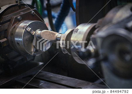 A heavy industrial worker in a factory works with metal on angle grinders while hot sparks are produced as a result. 84494792