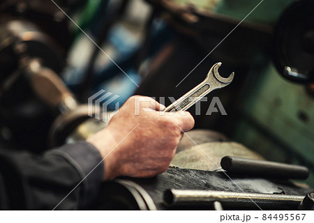 A heavy industrial worker in a factory works with metal on angle grinders while hot sparks are produced as a result. 84495567