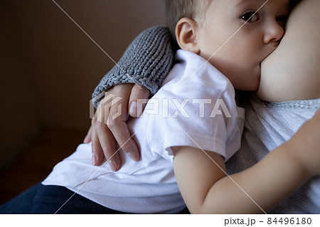 young woman breastfeeding her little son while sitting in a cozy armchair young woman breastfeeding her little son while sitting in a cozy armchair 84496180