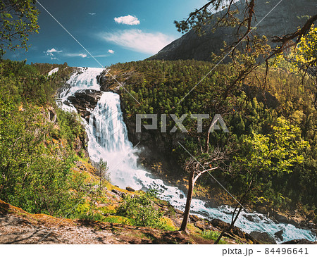 Kinsarvik, Hordaland, Norway. Waterfall Nyastolfossen In Hardangervidda Mountain Plateau. Nyastolsfossen in Spring Sunny Day. Height Of 115 m. Norwegian Landmark And Popular Destination 84496641
