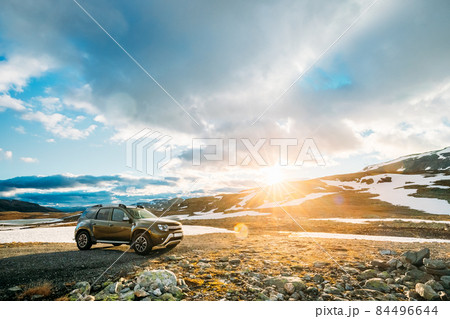 Aurlandsfjellet, Norway. Car SUV Parked Near Aurlandsfjellet Scenic Route Road In Summer Norwegian Landscape. Popular Destination In Sunset Lights. Sunshine 84496644