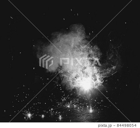 Welder at the factory in a welding mask welds metal parts, welding and sparks, black and white, close-up Welder at the factory in a welding mask welds metal parts, welding and sparks, black and white, close-up 84498054