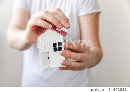 Woman hand holding toy model house isolated on white background. Real estate mortgage property insurance dream home concept. Offer of purchase rental house, family life, business real estate 84498851