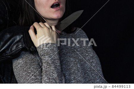 Man holding a knife at the girl's throat, black background 84499113