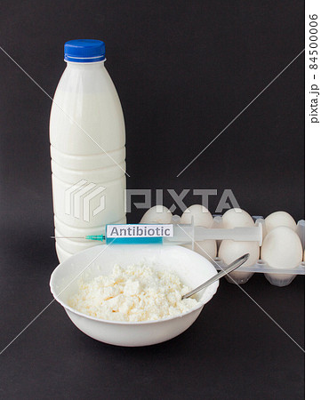 Milk in a bottle, cottage cheese and eggs on a black background, next there is a syringe with an antibiotic, close-up, antibiotic and dairy products, improvement Milk in a bottle, cottage cheese and eggs on a black background, next there is a syringe with an antibiotic, close-up, antibiotic and dairy products, improvement 84500006