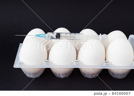 In an egg on a black background, a syringe is injected with a hormone and supplements, a close-up, testicles and antibiotic In an egg on a black background, a syringe is injected with a hormone and supplements, a close-up, testicles and antibiotic 84500007