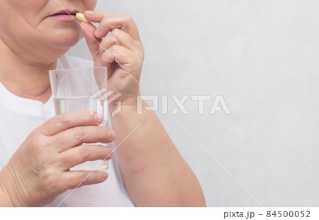 Woman drinking potassium iodide tablet and levothyroxine sodium, for the treatment of the thyroid gland, close-up, copy space Woman drinking potassium iodide tablet and levothyroxine sodium, for the treatment of the thyroid gland, close-up, copy space 84500052