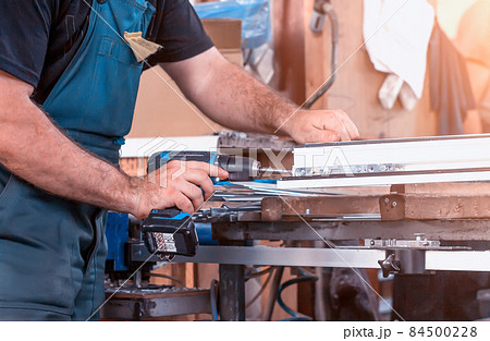 Production windows pvc, man screwed screwdriver hinged defense on the sash pvc frame, close-up, work 84500228