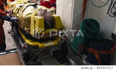 Crop paramedics loading injured survivor into vehicle Crop paramedics loading injured survivor into vehicle 84501417