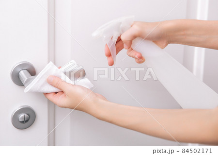 Cleaning white door handles with an antiseptic wet wipe and sanitizer spray. Disinfection in hospital and public spaces against corona virus. Woman hand using towel for cleaning home room door link. Cleaning white door handles with an antiseptic wet wipe and sanitizer spray. Disinfection in hospital and public spaces against corona virus. Woman hand using towel for cleaning home room door link. 84502171