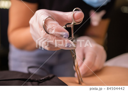 The first piercing. Dressing the earrings on the navel. Female piercing. The first piercing. Dressing the earrings on the navel. Female piercing. 84504442