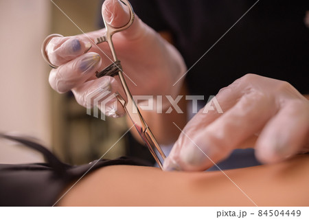 The first piercing. Dressing the earrings on the navel. Female piercing. The first piercing. Dressing the earrings on the navel. Female piercing. 84504449