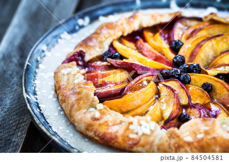 Rustic open pie (galette) with peach and berry 84504581