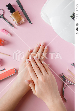 Spa procedure for nail care in a beauty salon. Female hands and tools for manicure on a pink background. Bodycare concept. Spa procedure for nail care in a beauty salon. Female hands and tools for manicure on a pink background. Bodycare concept. 84504709
