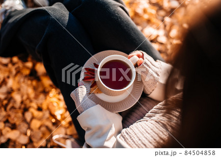 Young happy girl students, autumn park. A cup of hot tea, a cozy walk. Young happy girl students, autumn park. A cup of hot tea, a cozy walk. 84504858