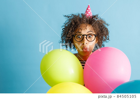 Multiethnic woman with party balloons standing in studio 84505105