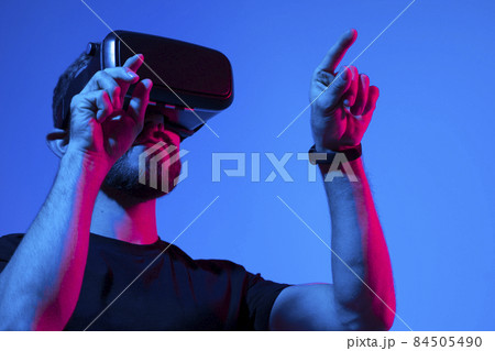 Young bearded man in virtual reality helmet plays online game in metaverse. Game simulates behavior in fictional world, gadgets and virtual reality addiction. Future technology concept. Young bearded man in virtual reality helmet plays online game in metaverse. Game simulates behavior in fictional world, gadgets and virtual reality addiction. Future technology concept. 84505490