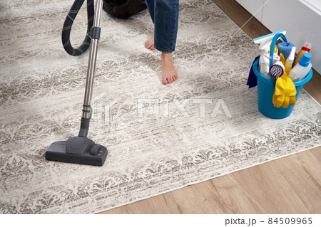 Woman cleaning the carpet with vacuum cleaner in the living room 84509965