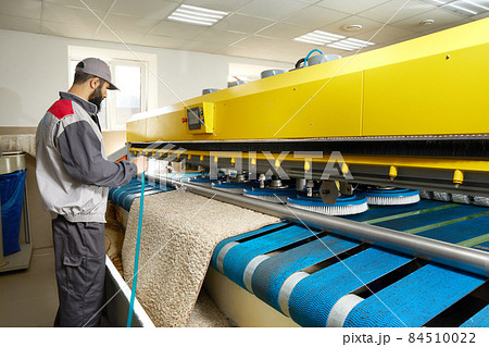 Man operating carpet automatic washing machine in professional laundry service Man operating carpet automatic washing machine in professional laundry service 84510022