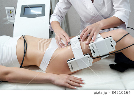 Beautiful woman getting electro stimulation therapy. Laser lipo equipment. Cosmetic fat reduce treatment. Anti cellulite procedure Beautiful woman getting electro stimulation therapy. Laser lipo equipment. Cosmetic fat reduce treatment. Anti cellulite procedure 84510164