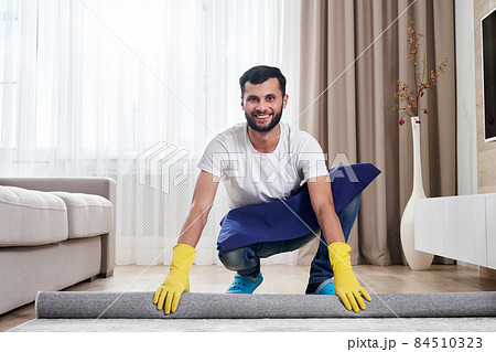 Close up of man unrolling carpet. Cleaning service concept 84510323