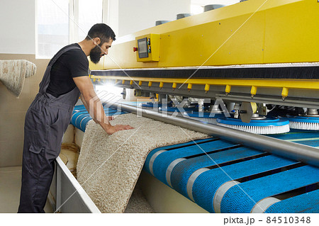Man operating carpet automatic washing machine in professional laundry service Man operating carpet automatic washing machine in professional laundry service 84510348
