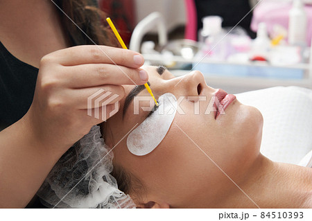 Eyelash extension procedure close up. Beautiful Woman with long lashes in a beauty salon 84510393