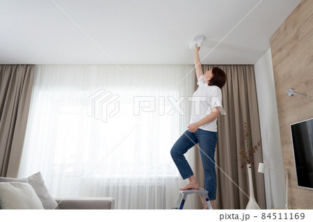 Woman cleaning ceiling with a mop. Housewife cleaning living room 84511169