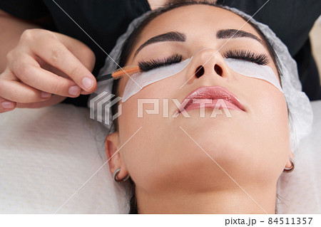 Cosmetologist making eyelash extention and correction using brush 84511357