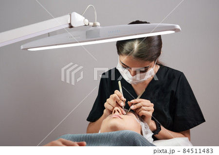 Eyelash Extension Procedure. Woman Eye with Long Eyelashes 84511483