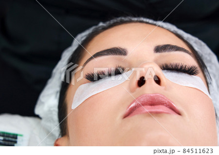Beautiful Woman with long lashes in a beauty salon. Eyelash extension procedure 84511623