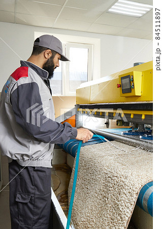 Man operating carpet automatic washing machine in professional laundry service Man operating carpet automatic washing machine in professional laundry service 84511897