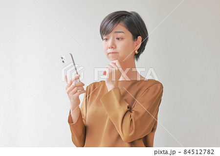困ってふくれっ面のスマホを見る女性 困ってふくれっ面のスマホを見る女性 84512782