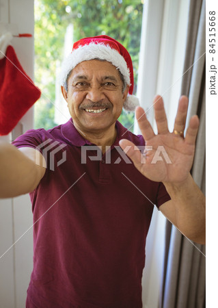 Portrait of happy biracial senior man in santa hat making christmas video call 84515668