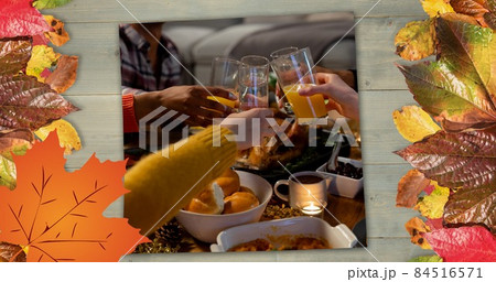 Composite image of people toasting drinks at thanksgiving dinner party and autumn leaves, copy space Composite image of people toasting drinks at thanksgiving dinner party and autumn leaves, copy space 84516571