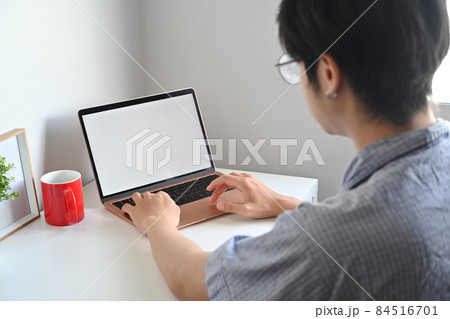 Rear view asian man browsing internet with laptop computer at home. 84516701