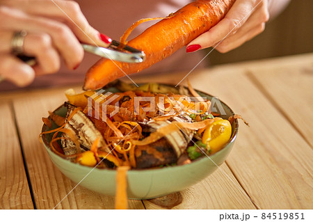 Women scraps peels carrots vegetable peeling, throws in compost bucket, organic composting 84519851