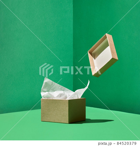 Craft box with wrapping paper inside and levitating box's cover on green back Craft box with wrapping paper inside and levitating box's cover on green back 84520379