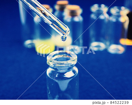 drop of liquid from a pipette into a medical bottle, research concept, new drugs and science, on a bright pink, blue and purple background drop of liquid from a pipette into a medical bottle, research concept, new drugs and science, on a bright pink, blue and purple background 84522239