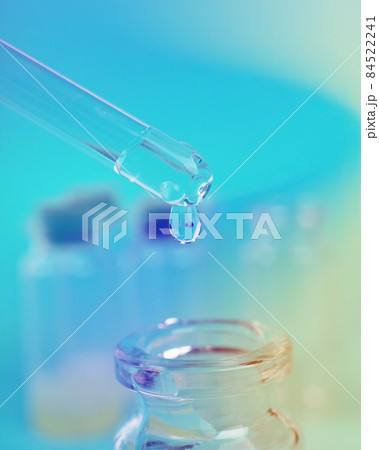 drop of liquid from a pipette into a medical bottle, research concept, new drugs and science, on a bright pink, blue and purple background 84522241