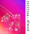 drop of liquid from a pipette into a medical bottle, research concept, new drugs and science, on a bright pink, blue and purple background 84522242