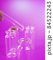 drop of liquid from a pipette into a medical bottle, research concept, new drugs and science, on a bright pink, blue and purple background 84522243