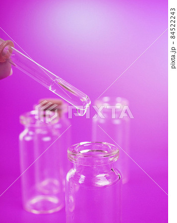drop of liquid from a pipette into a medical bottle, research concept, new drugs and science, on a bright pink, blue and purple background drop of liquid from a pipette into a medical bottle, research concept, new drugs and science, on a bright pink, blue and purple background 84522243