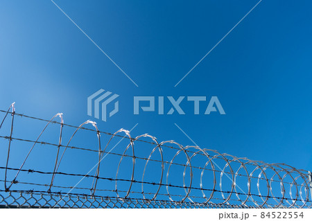 steel grating fence. coiled razor wire with its sharp steel barbs 84522554