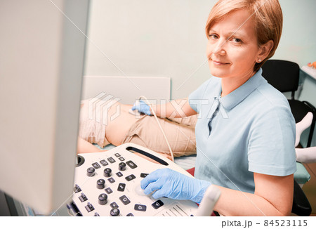 Gynecologist in sterile gloves examining female patient with ultrasound scanner while woman lying on daybed. Sonographer performing ultrasound scanning. Concept of ultrasound diagnostics. Gynecologist in sterile gloves examining female patient with ultrasound scanner while woman lying on daybed. Sonographer performing ultrasound scanning. Concept of ultrasound diagnostics. 84523115